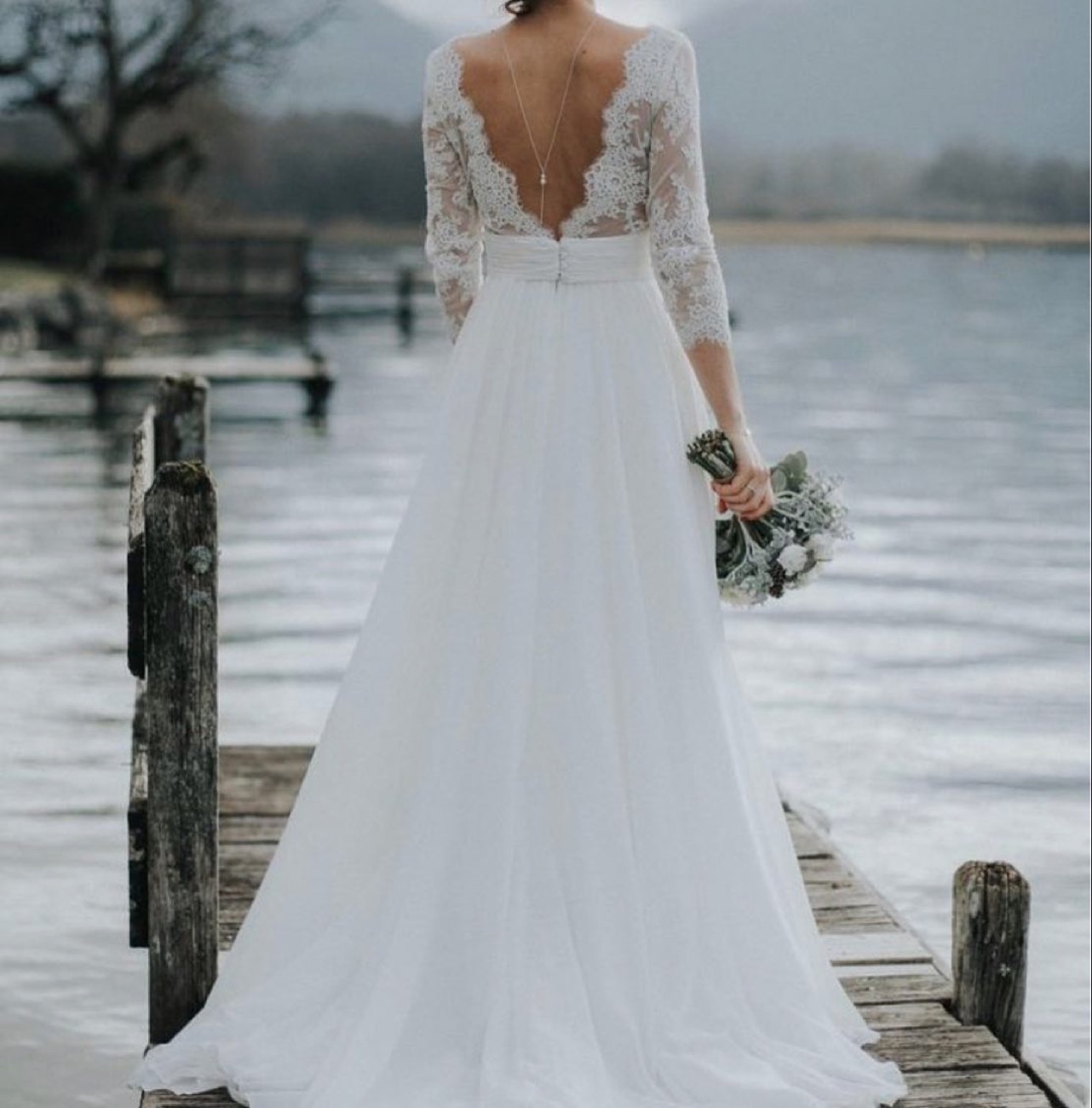 Mariée de dos, robe dos nu en dentelle, au bord de l'eau